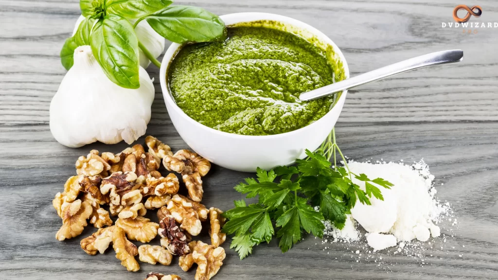 A spoonful of Jamaican Green Sauce being lifted from a glass jar, surrounded by fresh greens, set on a rustic dark background.