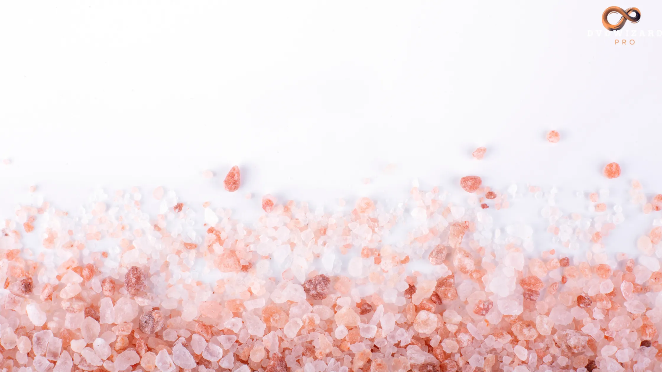 Coarse pink Tibetan salt crystals scattered on a white surface, showcasing their natural pink hues.