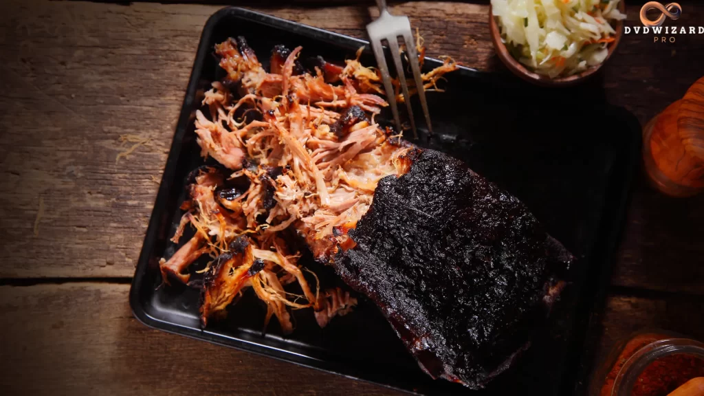 Pulled pork served on a black tray with a crispy bark and smoky texture.